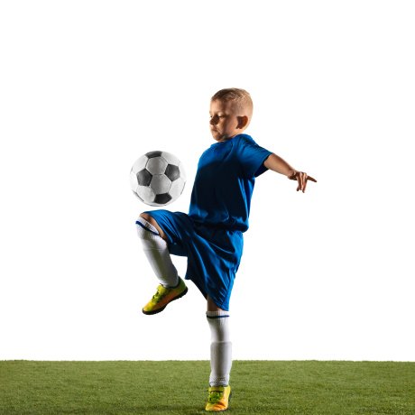 Young boy as a soccer or football player in sportwear making a feint or a kick with the ball for a goal on white studio background. Fit playing boy in action, movement, motion at game.
